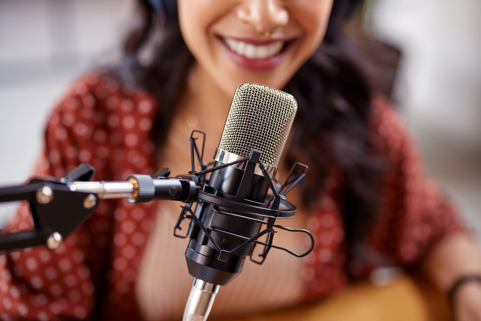 Close up of smiling woman recording podcast with professional mi